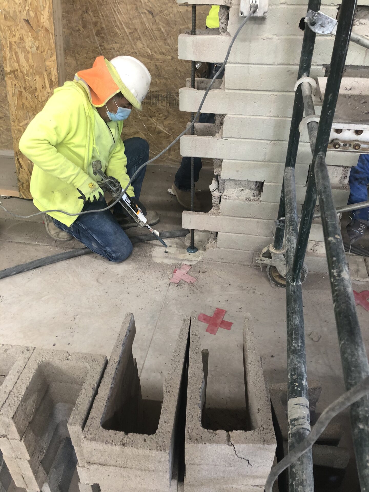 A man in yellow jacket using a hose to connect pipes.