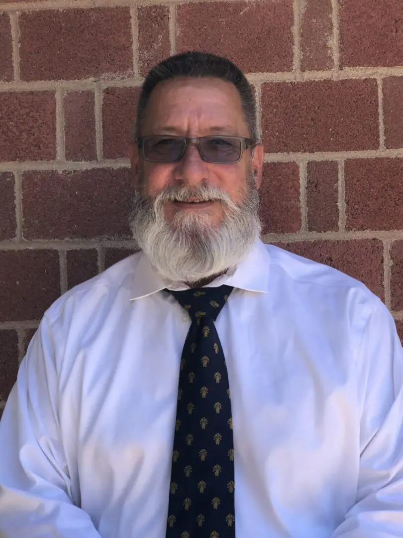 A man with a beard and glasses wearing a white shirt